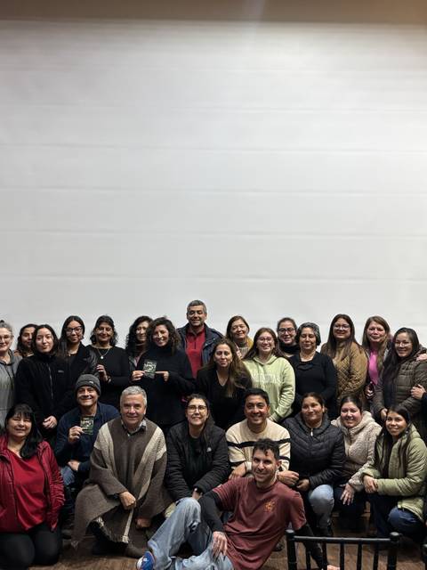 Un grupo grande de personas posando juntas en un evento en un salón amplio.