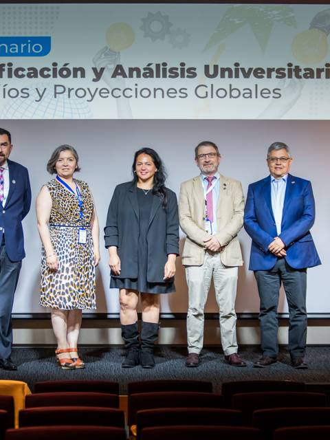 Una foto de un seminario sobre planificación y análisis universitario con varios expositores en el escenario.