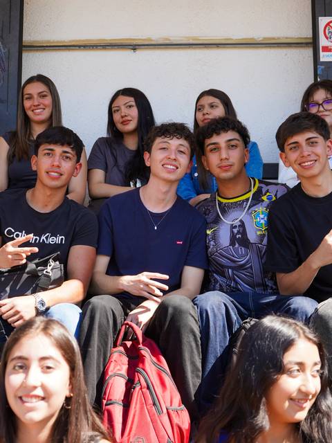 Un grupo de jóvenes sonrientes posando en un ambiente escolar.