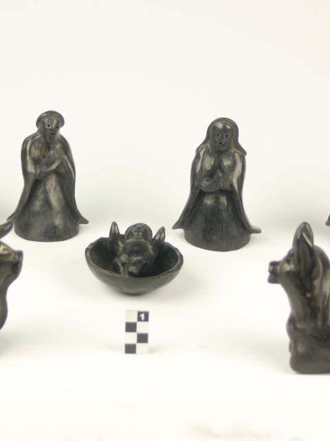 Conjunto de figuras de cerámica negra que representan diversas personas y animales.