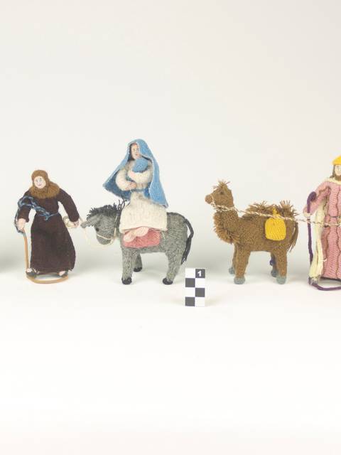 La imagen muestra figuras de cerámica que representan personas y camellos en una escena de pastoreo.