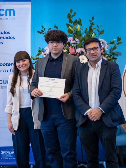 Un grupo de tres personas sonrientes sostiene un certificado en un evento institucional de la universidad.