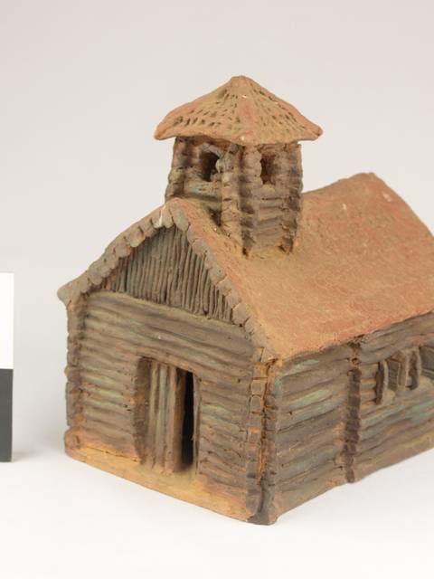 La imagen muestra una maqueta de una cabaña de madera con un techo de palapa.