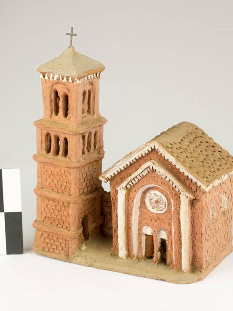 La imagen muestra un modelo en cerámica de una iglesia con torre campanario.