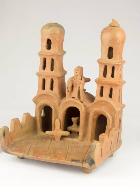 Una figura de cerámica con torres y una figura humana en el centro.
