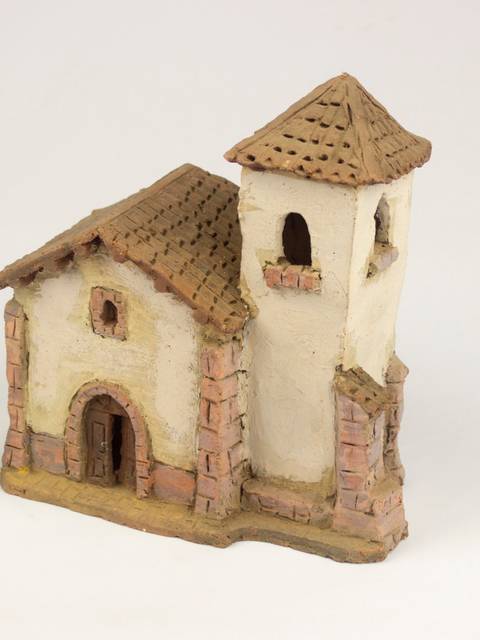 La imagen muestra una maqueta de una iglesia con detalles en cerámica y un campanario.