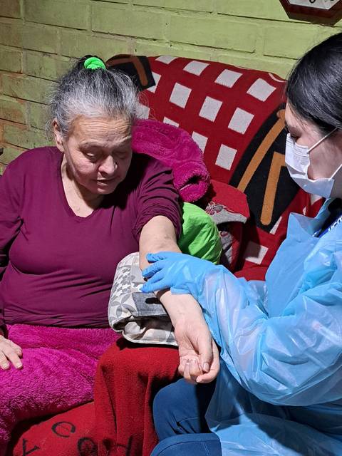 Una mujer mayor recibe atención médica en su hogar.