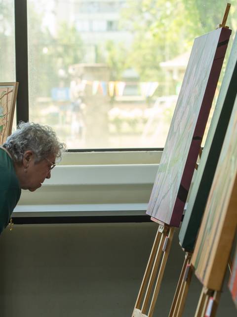 Dos mujeres observan atentamente una exposición de pinturas.