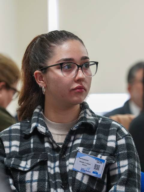 Una joven con lentes escucha atentamente en una reunión.