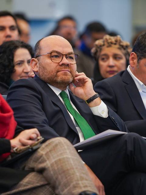 Un grupo de personas sentadas en un evento, mostrando atención y diferentes niveles de interacción con sus dispositivos.
