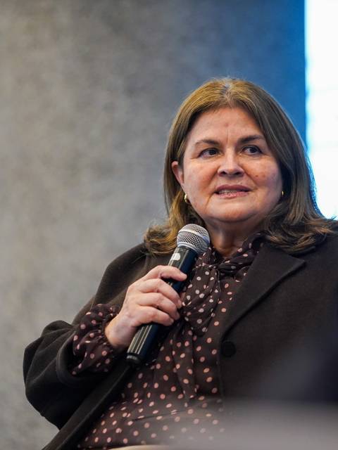 Una mujer hablando con un micrófono en un panel de conversación.