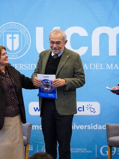 En el evento de la UCM, tres personas interactúan mientras sostienen un libro en un ambiente académico.