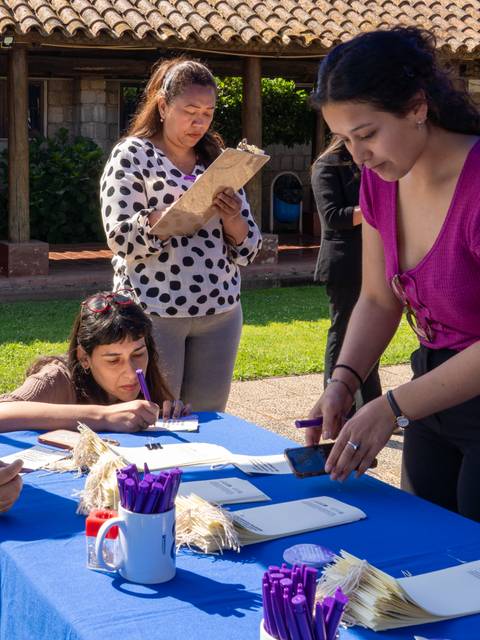 En la imagen se observa un grupo de mujeres en un evento al aire libre, todas participando en alguna actividad relacionada con la organización del mismo.