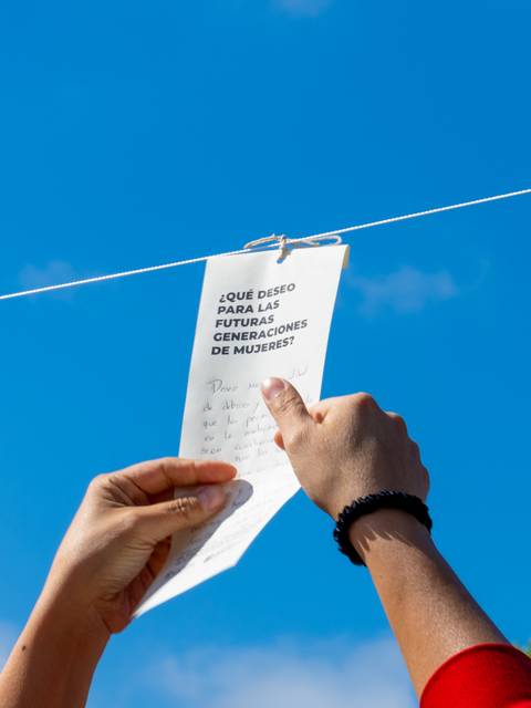 Una persona sostiene un papel con un mensaje en un día soleado.