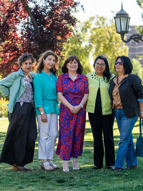 Un grupo de cinco mujeres posando en un parque bajo la luz del sol.