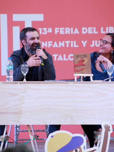 Una pareja de presentadores dialoga en una feria del libro infantil y juvenil.