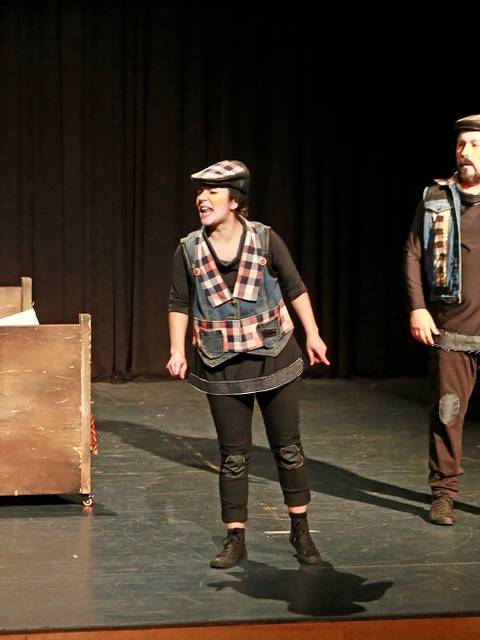 Tres actores representan una escena de teatro sobre un escenario.