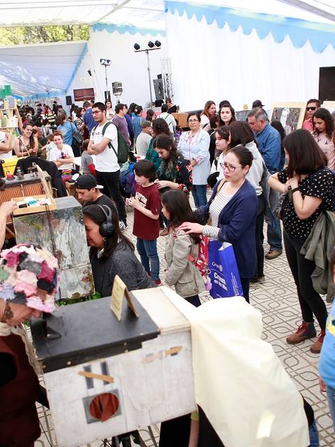 Una gran multitud disfruta de un evento al aire libre con actividades y exposiciones.