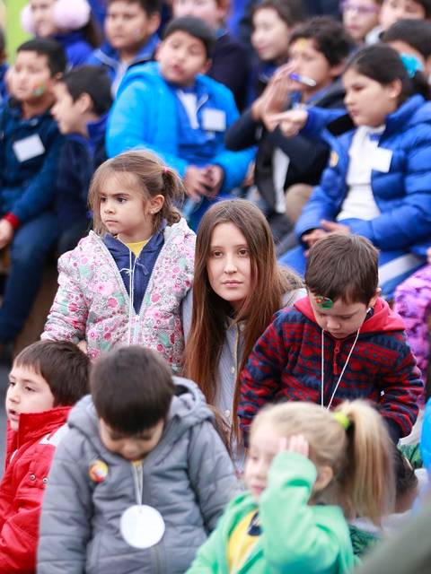 Un grupo de niños y adultos sentados en un evento al aire libre.