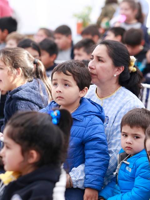 Un grupo de niños y un adulto se sientan observando un evento en un ambiente familiar.