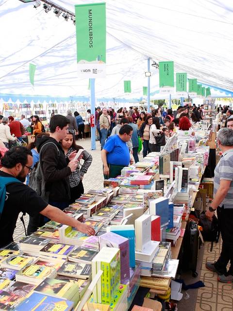 Una multitud de personas recorriendo un festival de libros bajo una gran carpa.