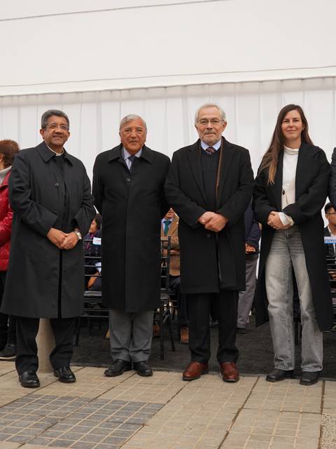 Un grupo de personas bien vestidas posando en un evento al aire libre.