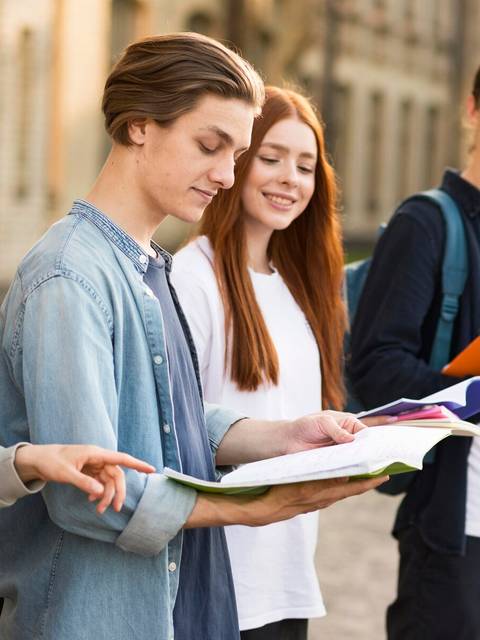 Un grupo de estudiantes revisa libros y cuadernos en un entorno al aire libre.