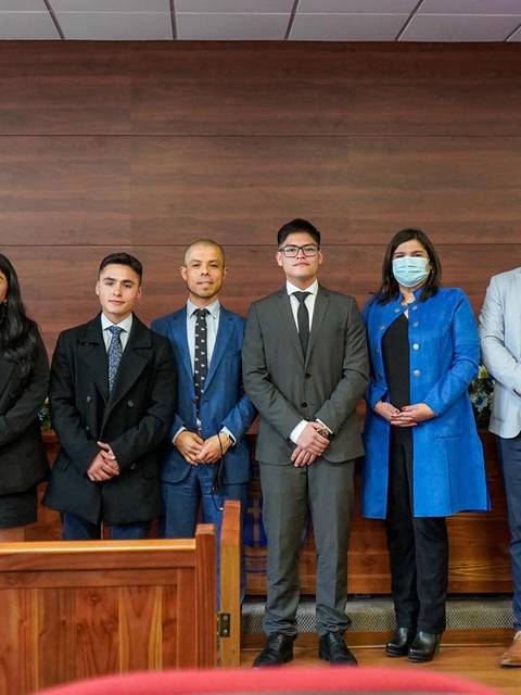 Un grupo de personas posando en un ambiente formal con banderas de Chile al fondo.
