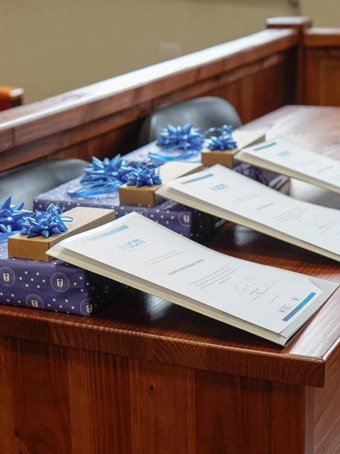 Una mesa de madera con certificados y regalos decorados en una sala de tribunal.