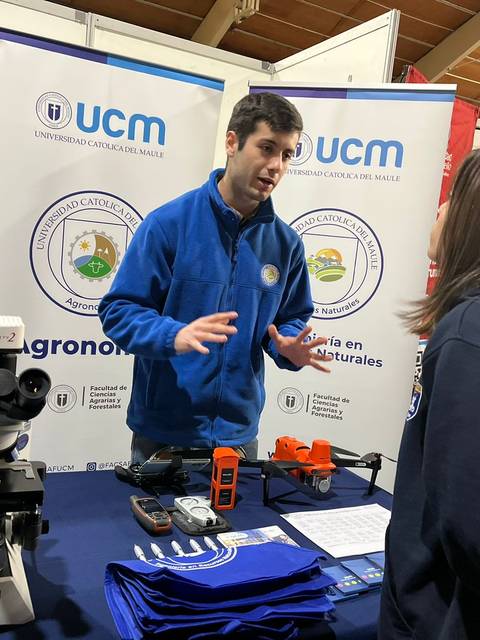 Un estudiante presenta información sobre agronomía en un evento educativo.