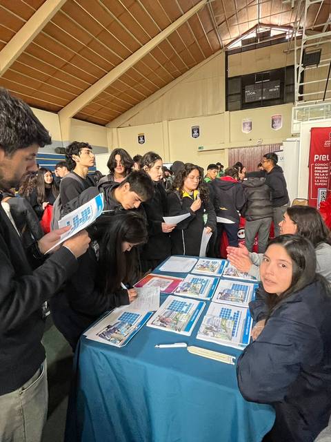 Una feria de orientación educativa con estudiantes interactuando en un stand.