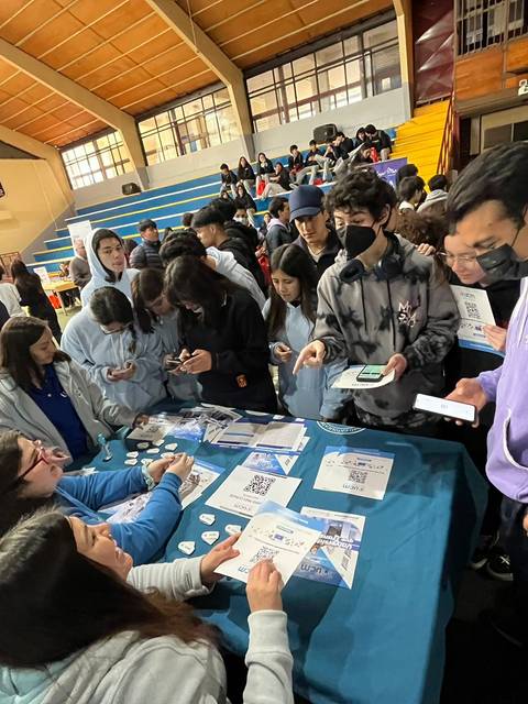 Un grupo de jóvenes interactuando en un evento en un gimnasio escolar.