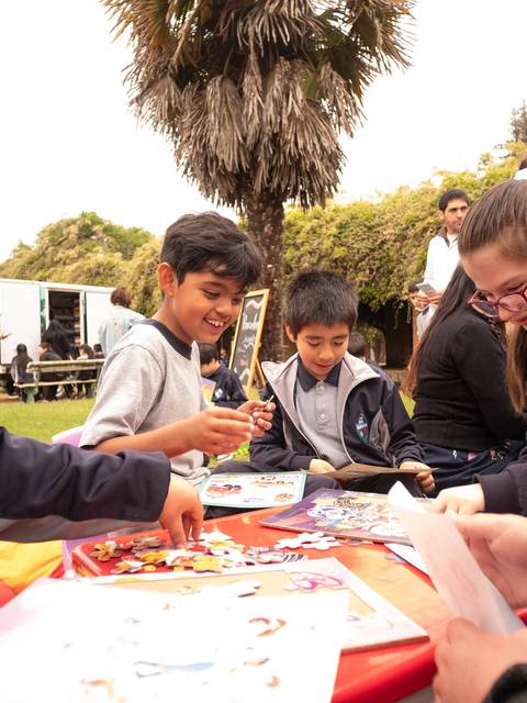Niños y niñas se divierten juntos realizando manualidades al aire libre.