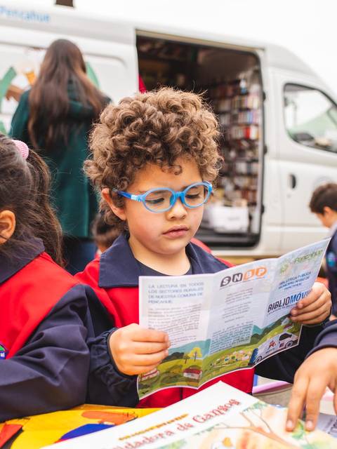 Un grupo de niños en una actividad educativa al aire libre, leyendo y explorando libros.