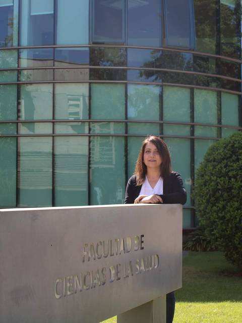 Dos mujeres posan frente a un edificio moderno de la Facultad de Ciencias de la Salud.