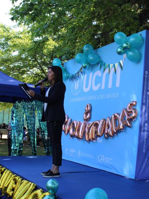 Una presentación en un evento al aire libre con decoraciones y un escenario azul.