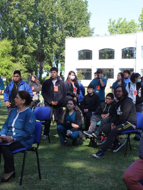 Un grupo de personas se reúne en un espacio al aire libre, en un ambiente relajado y entre árboles.