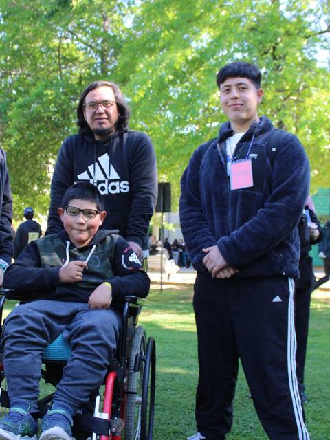 Un grupo de cuatro personas posando en un parque, con un joven en silla de ruedas en el centro.