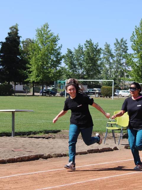 Dos personas corren en una pista de atletismo en un entorno al aire libre.
