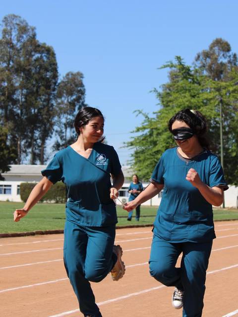 Dos mujeres corriendo en una pista de atletismo, una de ellas con los ojos vendados.