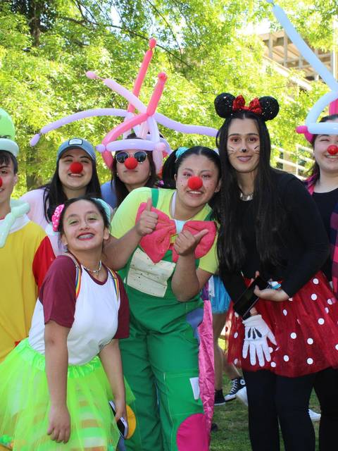Grupo de personas disfrazadas de payasos sonriendo en un parque.