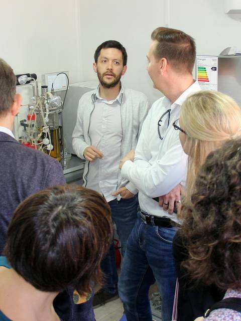Un grupo de personas observa y escucha a un presentador en un entorno de laboratorio.