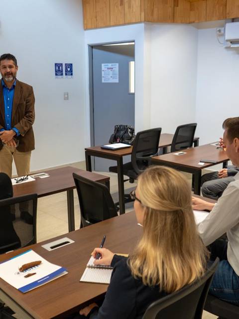 Un grupo de personas asiste a una presentación en un aula moderna.