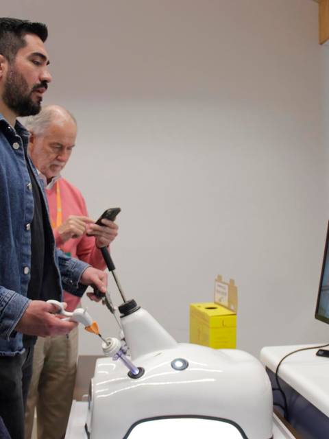 Un grupo de personas observa una demostración de un dispositivo médico en una sala de exhibición.