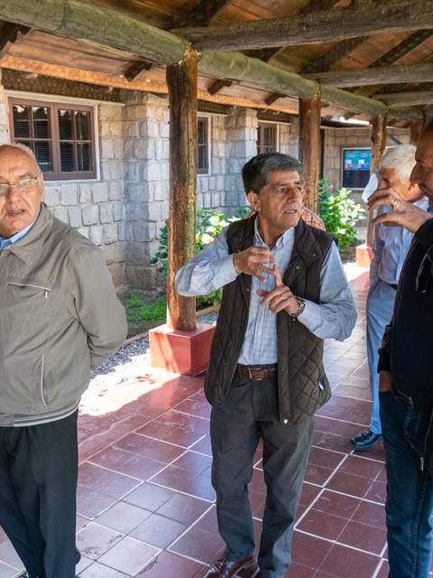 Un grupo de hombres conversando en un pasillo de un edificio con estructuras de madera.