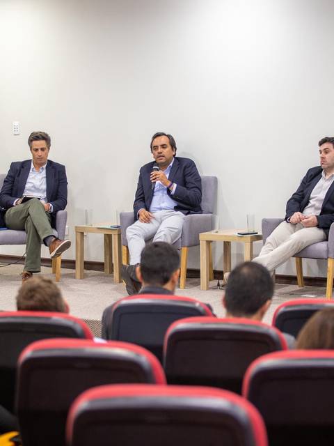 Un panel de discusión con cinco oradores sentados frente a una audiencia.