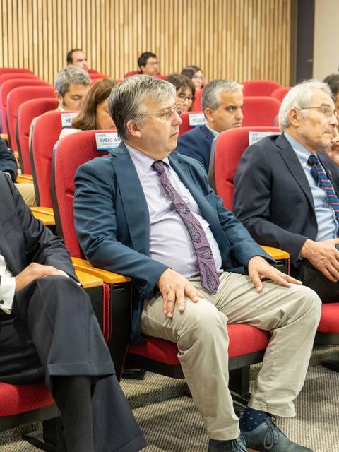 Tres hombres sentados en un auditorio durante un evento.