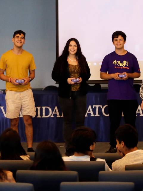 Un grupo de estudiantes sostiene premios durante un evento en la universidad.