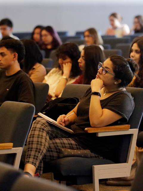 Un grupo de personas asiste a una conferencia en un auditorio.