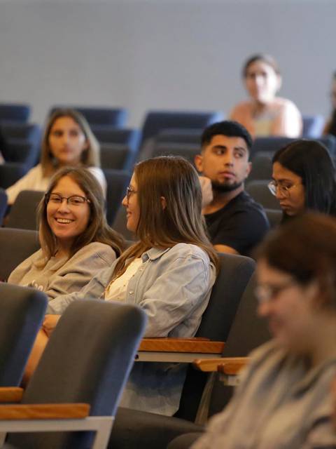 Un grupo de jóvenes sentados en una sala de conferencias, conversando y mirando hacia la cámara.